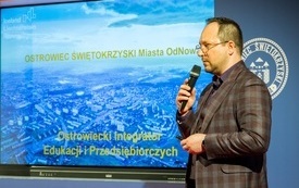 Wiceprezydent Dominik Smoliński przemawia, w tle niebieski ekran z napisem Ostrowiec Świętokrzyski Miasto Odnowa