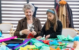 Zdjęcie przedstawia starszą kobietę i dziewczynkę podczas warsztat&oacute;w wielkanocnych na Wielkanocnym Ryneczku 2022