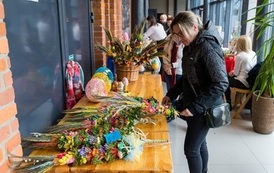 Zdjęcie przedstawia kobietę przy stole z ozdobami świątecznymi na Wielkanocnym Ryneczku 2022