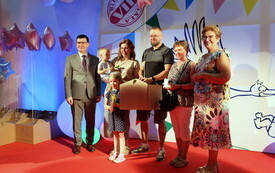 Na scenie siedem radosnych os&oacute;b w tym dzieci. Jedna trzyma wyprawkę dla dziecka od prezydenta. Prezydent stoi wraz z nimi z uśmiechem. Obok stoi r&oacute;wnież Przewodnicząca Rady Miasta.