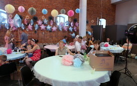 Uczestnicy gali za stołami. Siedzą przy nich z dziećmi z uśmiechami