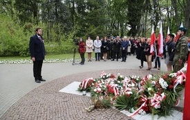 Osoby oddają hołd przed pomnikiem