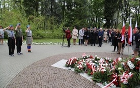 Osoby oddają hołd przed pomnikiem