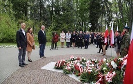 Osoby oddają hołd przed pomnikiem