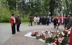 Osoby oddają hołd przed pomnikiem