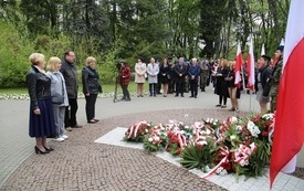 Osoby oddają hołd przed pomnikiem