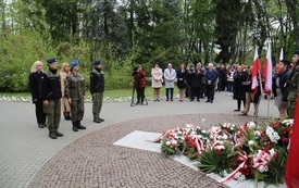 Osoby oddają hołd przed pomnikiem