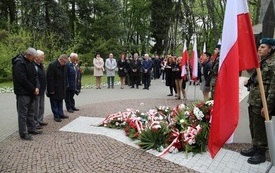 Osoby oddają hołd przed pomnikiem