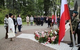 Osoby oddają hołd przed pomnikiem