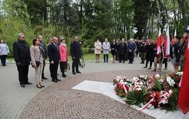 Osoby oddają hołd przed pomnikiem