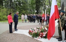 Osoby oddają hołd przed pomnikiem