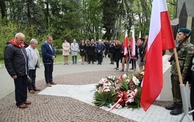 Osoby oddają hołd przed pomnikiem