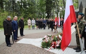 Osoby oddają hołd przed pomnikiem