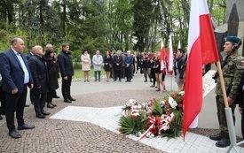 Osoby oddają hołd przed pomnikiem