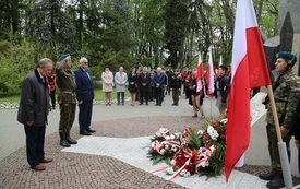 Osoby oddają hołd przed pomnikiem