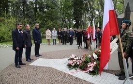 Osoby oddają hołd przed pomnikiem