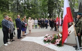 Osoby oddają hołd przed pomnikiem