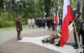 Osoby oddają hołd przed pomnikiem