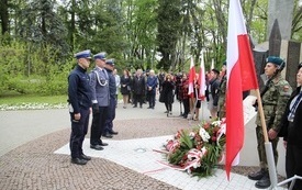 Osoby oddają hołd przed pomnikiem