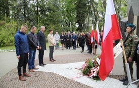 Osoby oddają hołd przed pomnikiem