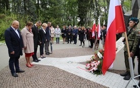 Osoby oddają hołd przed pomnikiem