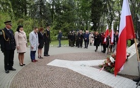 Osoby oddają hołd przed pomnikiem