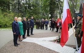 Osoby oddają hołd przed pomnikiem