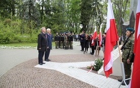 Osoby oddają hołd przed pomnikiem