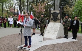 Osoba przemawia pod pomnikiem