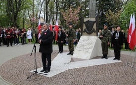 Osoba przemawia pod pomnikiem