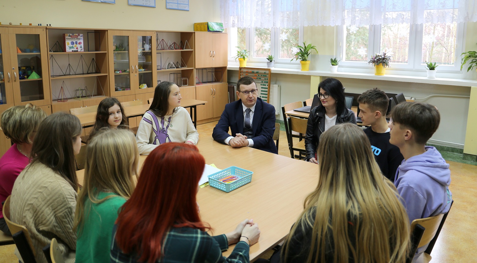 uczniowie z Prezydentem siedzą przy stole i rozmawiają.