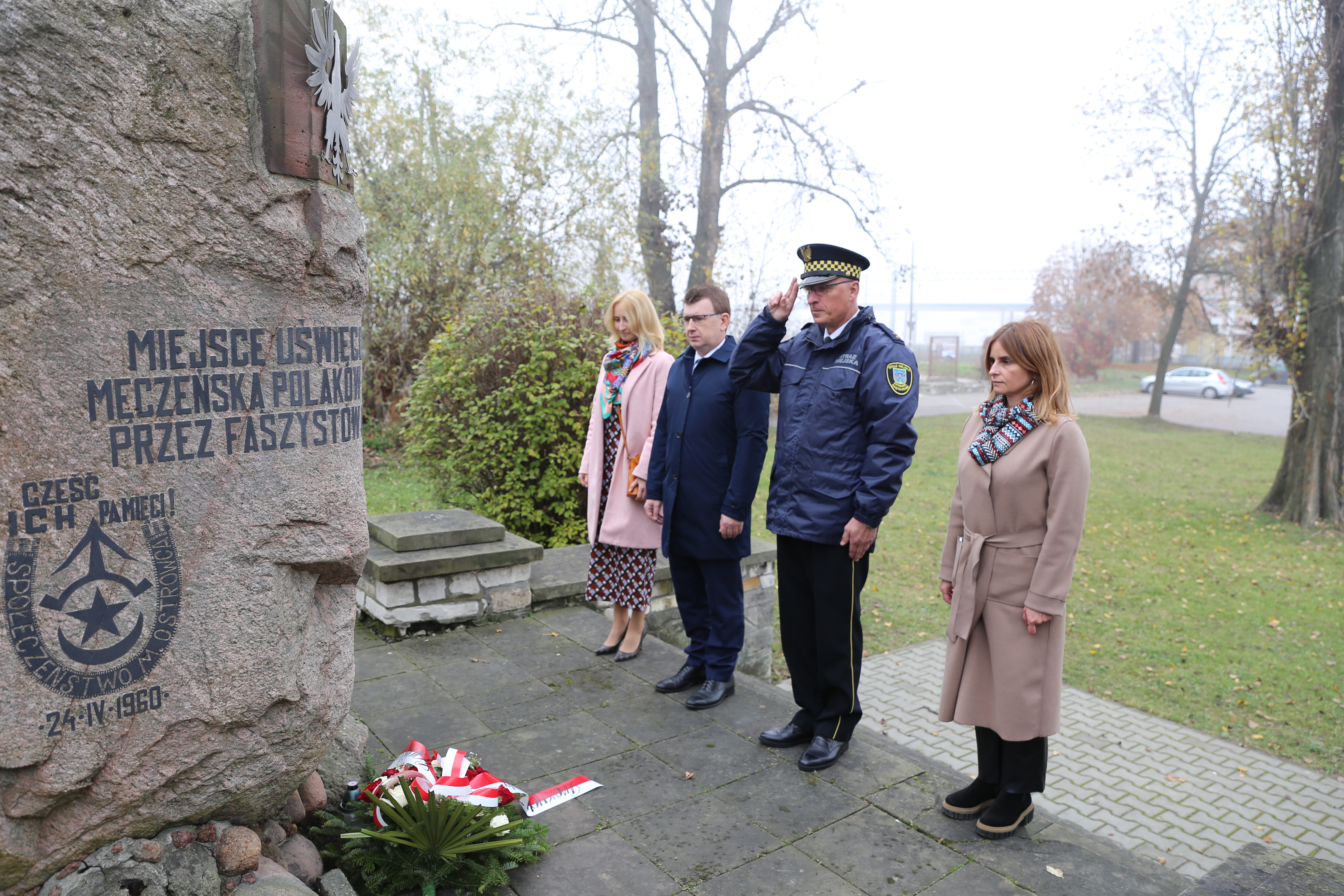 Osoby oddają hołd przed pomnikiem.