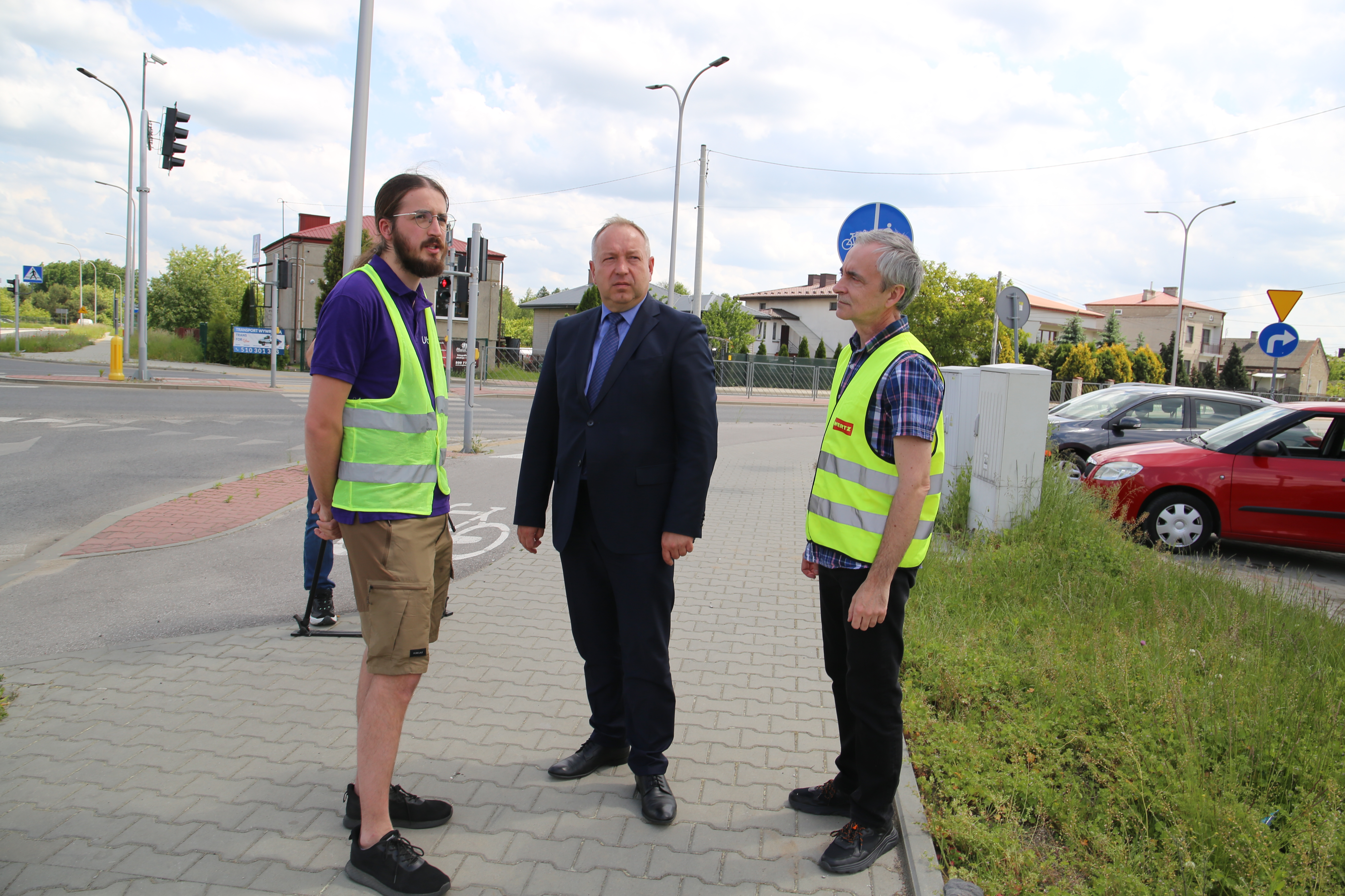 Osoby stoją przy skrzyżowaniu